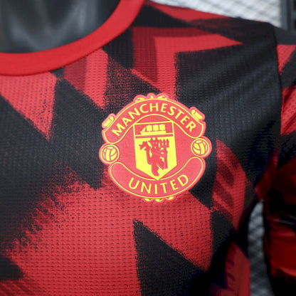 Camisa vermelha e preta do Manchester United para treino pré-jogo 2025/26, versão jogador